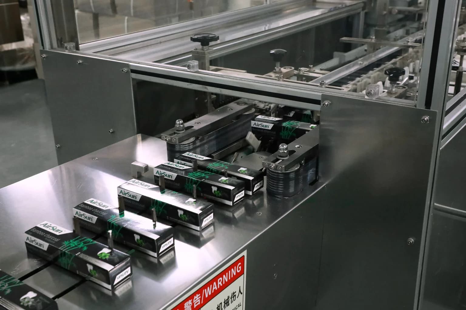 Airsun toothpaste cartons moving through packaging equipment on the production line.