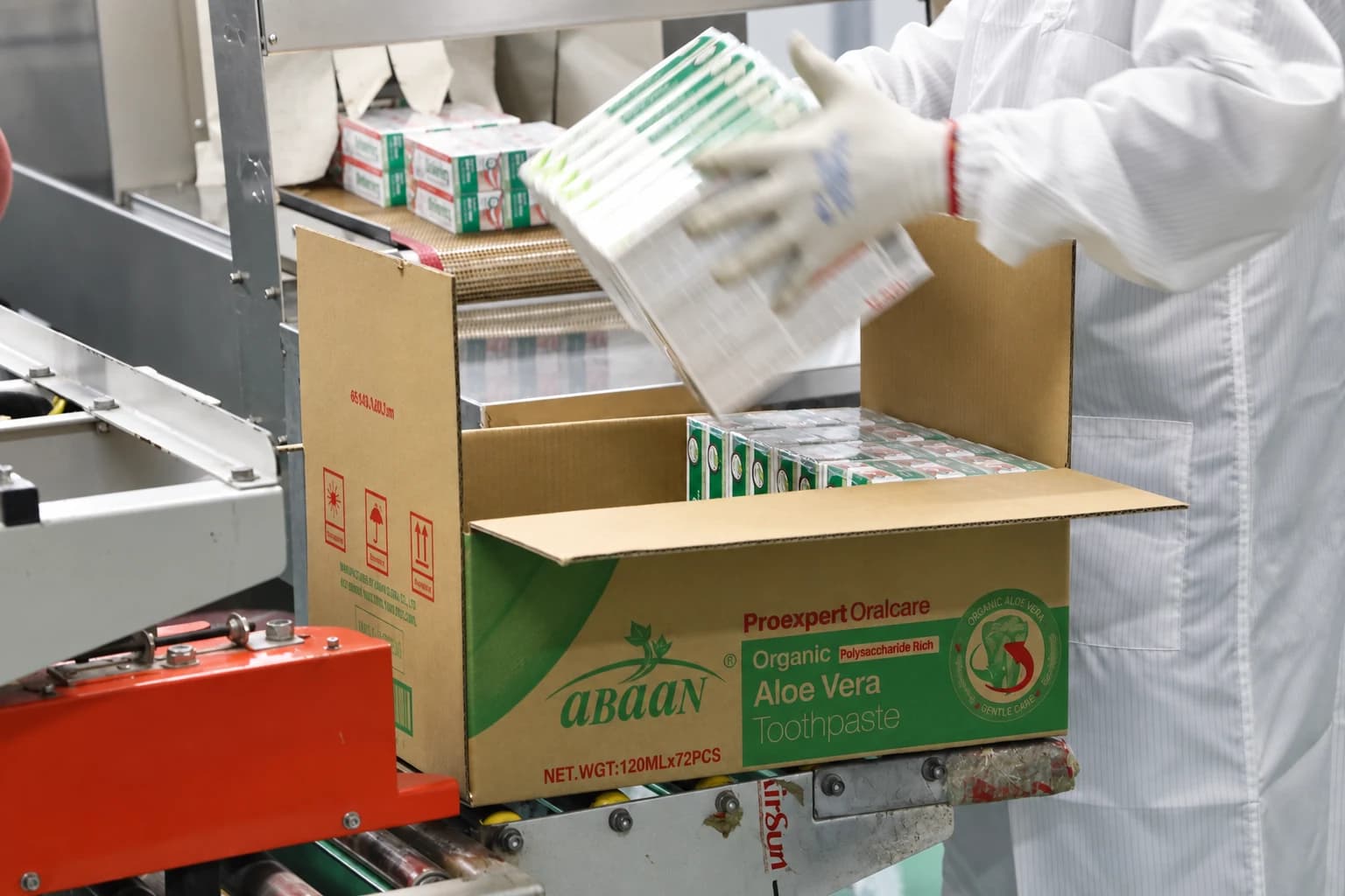 An operator packing toothpaste cartons into a shipping case on the production line.